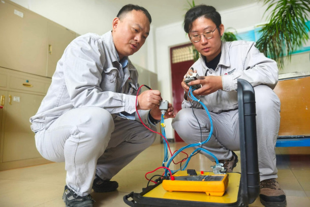 1758523187751096805.jpg 图为配电班QC小组成员对自主研制的试验辅助装置进行调试.jpg